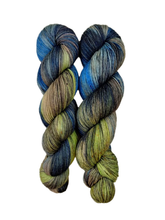 A skein of hand-dyed fingering/sock yarn color green brown blue grey black speckles