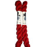 Two red skeins of yarn with a label on a white background