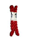 Two red skeins of yarn with a label on a white background