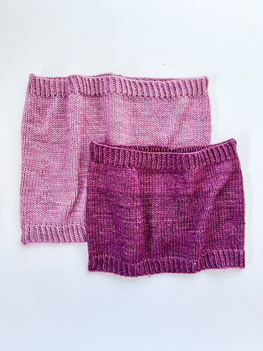 2 Base Doodle Cowls knit in various sizes in the colors light purple and dark purple yarn