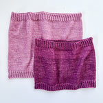 2 Base Doodle Cowls knit in various sizes in the colors light purple and dark purple yarn
