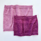 2 Base Doodle Cowls knit in various sizes in the colors light purple and dark purple yarn