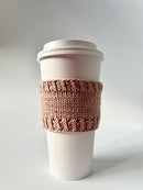 A Base Doodle Cup Cozy knit in light brown yarn on a disposable cup