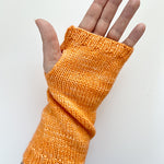 A Base Doodle Fingerless Mitt knit in a orange yarn worn on a hand