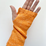 A Base Doodle Fingerless Mitt knit in a orange yarn worn on a hand