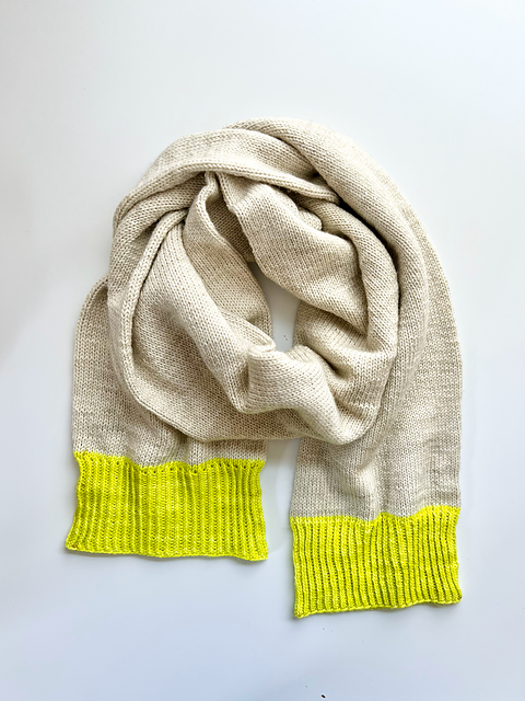 A Base Doodle Scarf knit in an off-white color with bright yellow ends