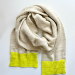 A Base Doodle Scarf knit in an off-white color with bright yellow ends