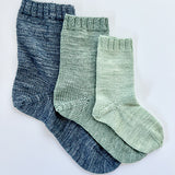 3 Base Doodle Socks knit in various sizes in navy blue green and light green yarn
