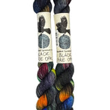 Two mini skeins of wool yarn hand dyed in Wyoming in the color black red orange yellow blue green