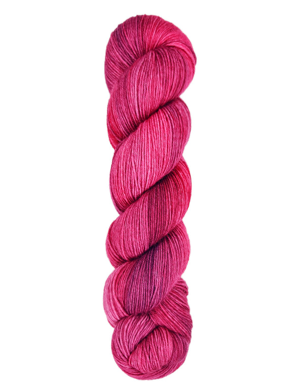 A skein of hand-dyed fingering/sock yarn color red pink