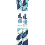 Blackbird Sycamore Fingering Mini Skein color variegated dark blue with streaks of light blue and white, and flecks of yellow and black