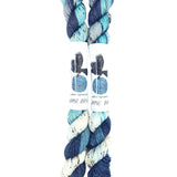 Blackbird Sycamore Fingering Mini Skein color variegated dark blue with streaks of light blue and white, and flecks of yellow and black