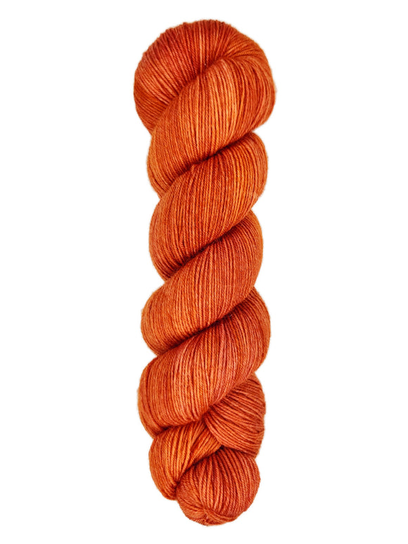 A skein of hand-dyed fingering/sock yarn color burnt orange
