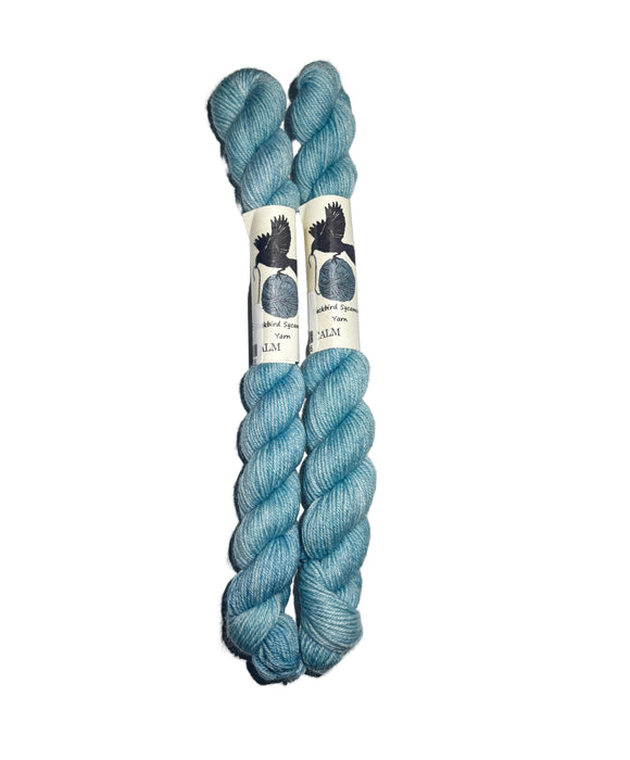 Two skeins of blue yarn with labels on a white background