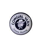 Small pin button with the cowgirl yarn logo on it