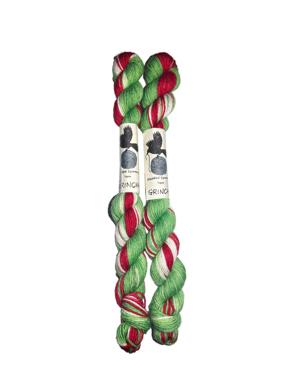 Two skeins of red, green, and white yarn on a white background