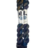 Two skeins of yarn in the colors brown grey blue purple on a white background