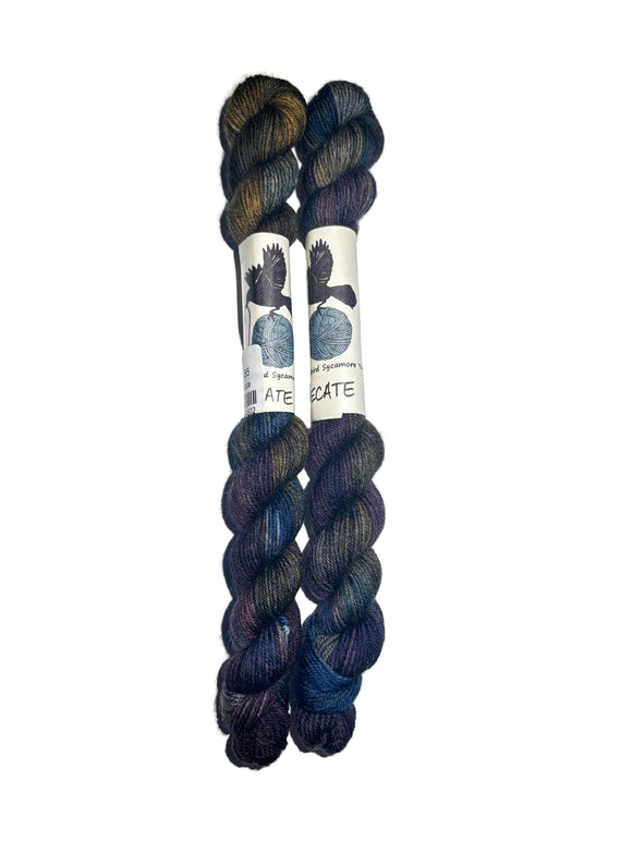 Two skeins of yarn in the colors brown grey blue purple on a white background