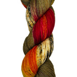 Skein of hand dyed fingering weight yarn in the color brown offwhite red orange black speckles
