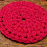 A circular crocheted, red coaster