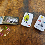 Small notion tins with a few stitch markers on a wooden surface