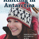 Knitting in Antarctica. Woman with red coat; red, white and black penguin hat