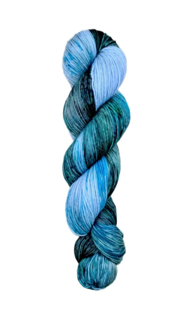 A skein of hand-dyed fingering/sock yarn color blue green black speckles