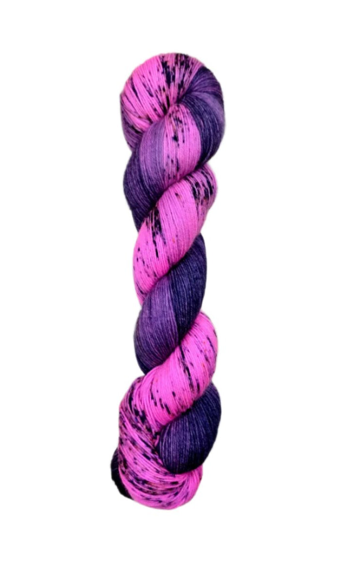 A skein of hand-dyed fingering/sock yarn color pink purple dark navy black speckles