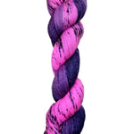 A skein of hand-dyed fingering/sock yarn color pink purple dark navy black speckles