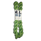 Two skeins of green yarn with labels on a white background