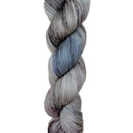 A skein of hand-dyed fingering/sock yarn color grey blue black speckles