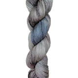 A skein of hand-dyed fingering/sock yarn color grey blue black speckles