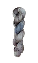 A skein of hand-dyed fingering/sock yarn color grey blue black speckles