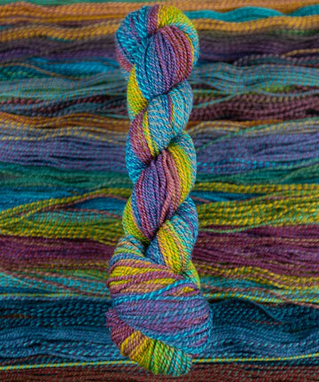 Skein of multicolored handspun looking wool yarn in the colors blue purple yellow orange green 