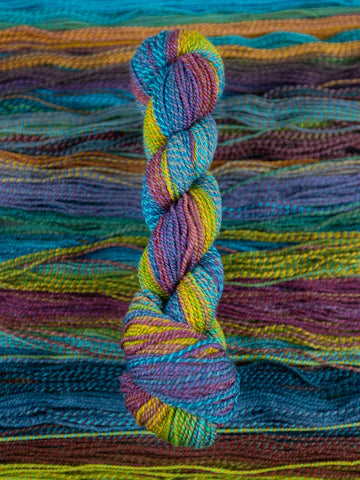 Skein of multicolored handspun looking wool yarn in the colors blue purple yellow orange green 