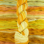 Skein of multicolored handspun looking wool yarn in the colors yellow white orange 