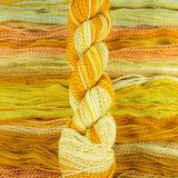 Skein of multicolored handspun looking wool yarn in the colors yellow white orange 