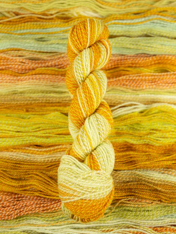 Skein of multicolored handspun looking wool yarn in the colors yellow white orange 