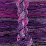 Skein of multicolored handspun looking wool yarn in the colors white dark purple light purple pink dark grey