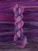 Skein of multicolored handspun looking wool yarn in the colors white dark purple light purple pink dark grey