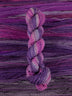 Skein of multicolored handspun looking wool yarn in the colors white dark purple light purple pink dark grey
