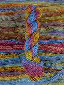 Skein of multicolored handspun looking wool yarn in the colors blue magenta orange yellow purple