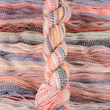 Skein of multicolored handspun looking wool yarn in the colors off-white black orange pink grey