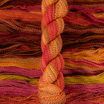 Skein of multicolored handspun looking wool yarn in the colors red pink yellow orange brown
