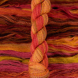 Skein of multicolored handspun looking wool yarn in the colors red pink yellow orange brown