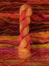 Skein of multicolored handspun looking wool yarn in the colors red pink yellow orange brown