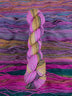 Skein of multicolored handspun looking wool yarn in the colors pink teal yellow burgundy purple 