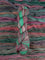 Skein of multicolored handspun looking wool yarn in the colors green pink grey teal brown