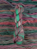 Skein of multicolored handspun looking wool yarn in the colors green pink grey teal brown