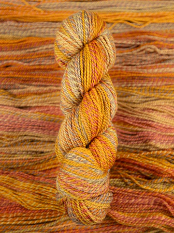 Skein of multicolored handspun looking wool yarn in the colors grey yellow orange off-white red brown
